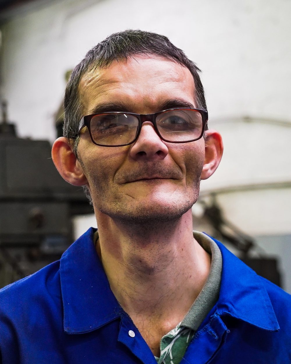 Jaco van Wyk in the Metal Workshop, wearing his blue work overalls and glasses