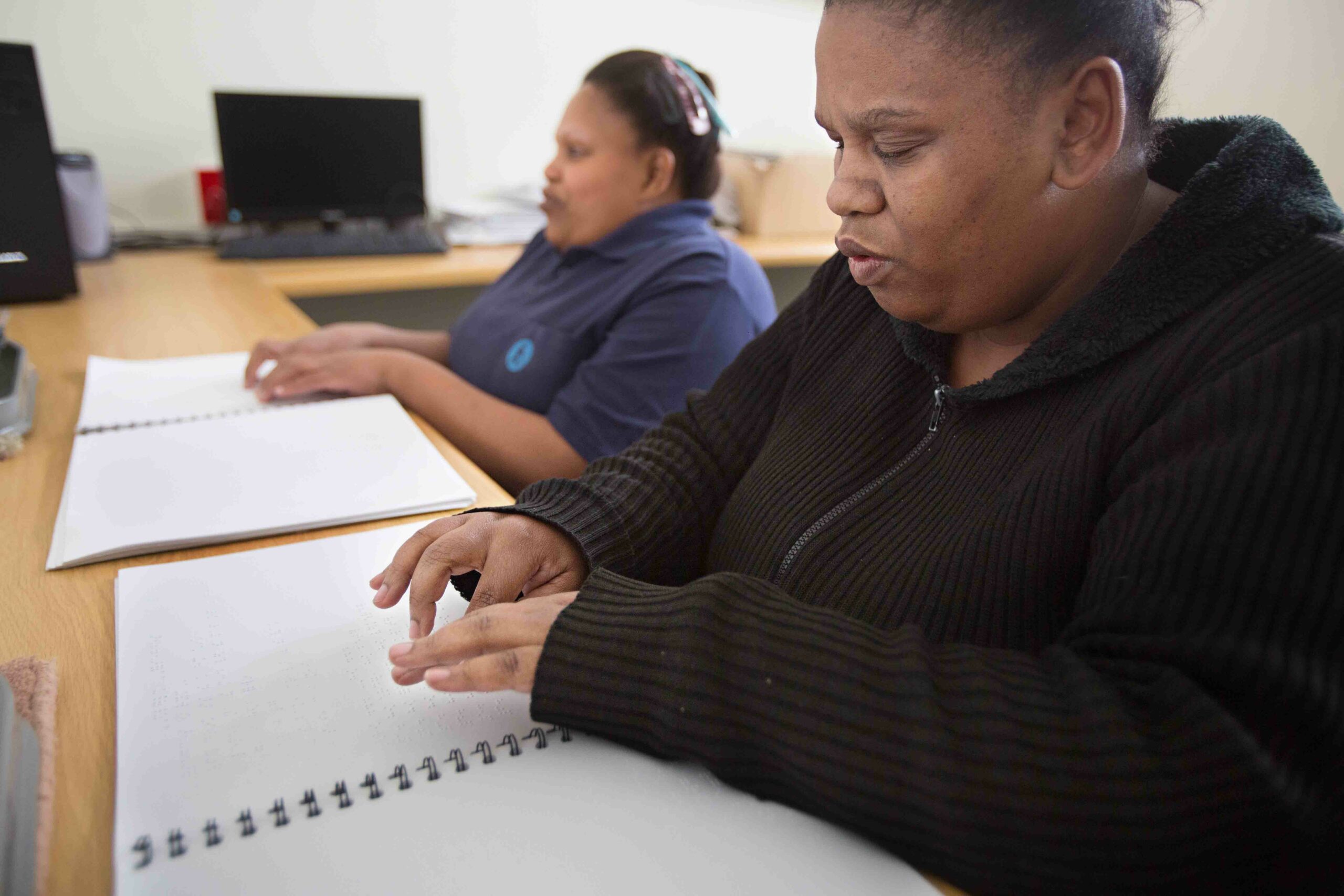 Two visually impaired persons reading braille